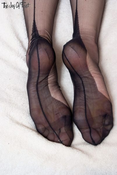 Голая девушка Лотти снимает свои черные прозрачные чулки, чтобы позировать с сексуальными босыми ногами