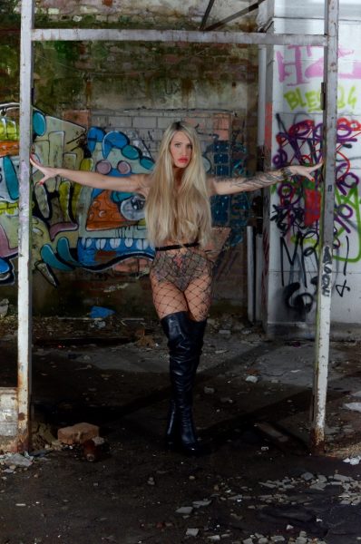 Татуированная блондинка с большими сиськами моделирует соло на фоне заполненных граффити стен