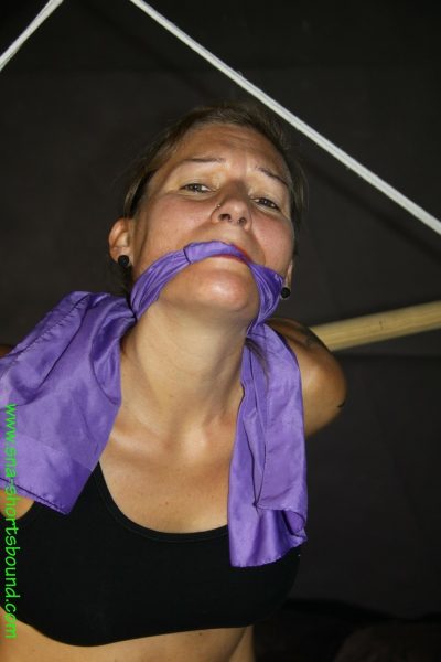 Татуированная девушка с кляпом во рту, скованная в неудобной позе