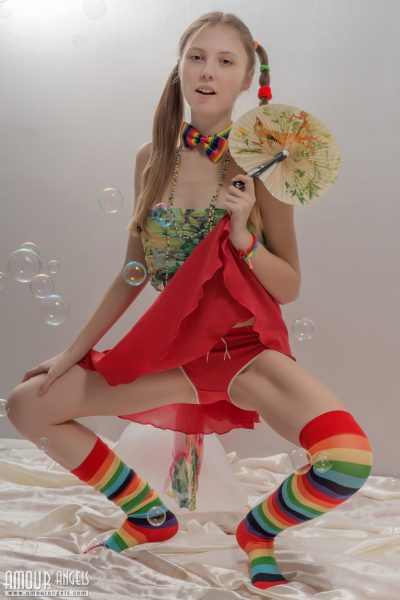 Худенькая девочка-подросток в косичках и разноцветных носках снимает с себя одежду