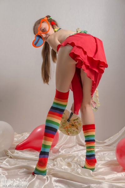 Худенькая девочка-подросток в косичках и разноцветных носках снимает с себя одежду