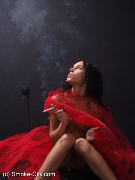 Темноволосая подросток показывает свое обнаженное тело во время курения сигареты